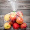 Apple fruit in plastic bag on wood table